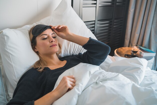 Ritratto di donna viaggiatrice che si rilassa e dorme pacificamente con la maschera del sonno nella camera d'albergo. Concetto di viaggio.