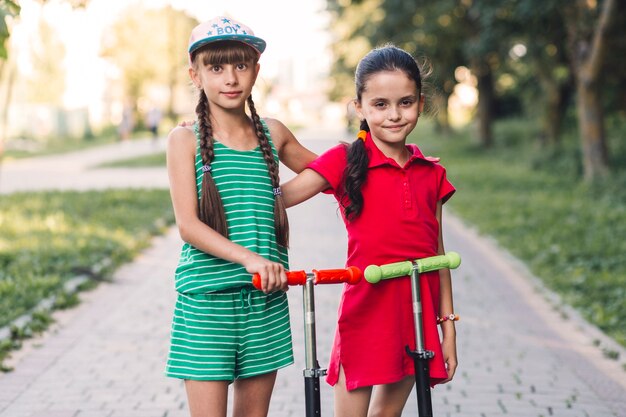 Ritratto di due amici femminili con il loro scooter da calcio