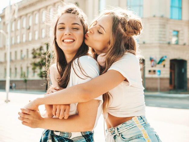 Ritratto di due giovani belle ragazze hipster sorridenti in vestiti di t-shirt bianca estiva alla moda