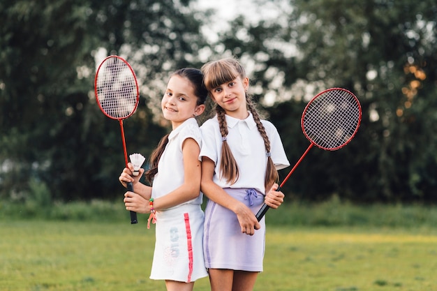 Ritratto di due ragazze sorridenti che tiene in mano il volano e il badminton