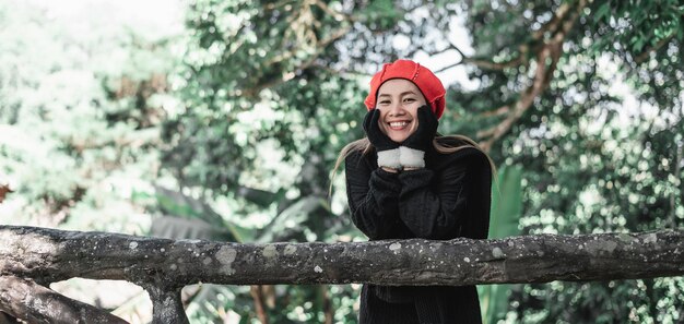 Ritratto di felice giovane donna asiatica in costume invernale nella foresta con spazio per la copia Concetto di vacanza e viaggio