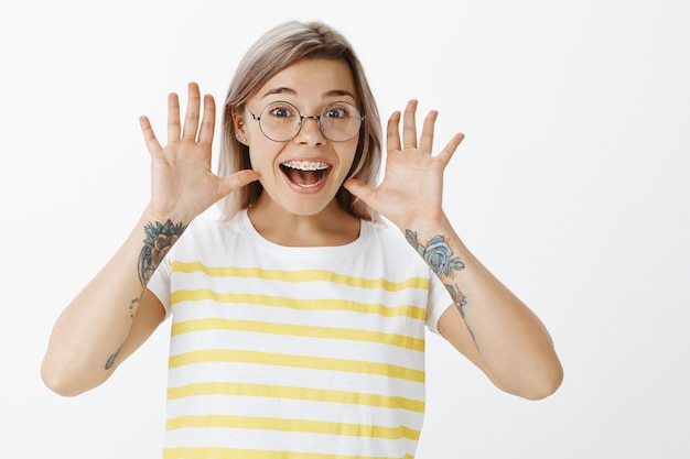 Ritratto di felice ragazza bionda con gli occhiali in posa in studio