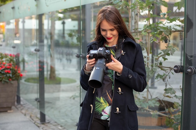 Ritratto di fotografa professionista per strada che fotografa su una macchina fotografica. Servizio fotografico in città