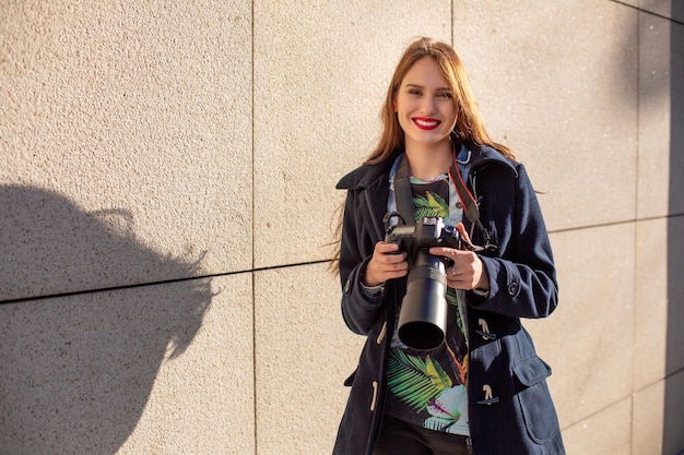 Ritratto di fotografa professionista per strada che fotografa su una macchina fotografica. Servizio fotografico in città