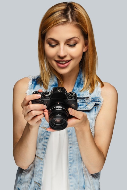 Ritratto di fotografo femminile biondo isolato su sfondo grigio.