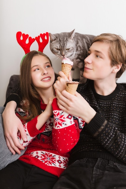 Ritratto di giovane bella coppia seduta sul divano di casa con il gelato in mano e un bel gatto vicino a quel gelato