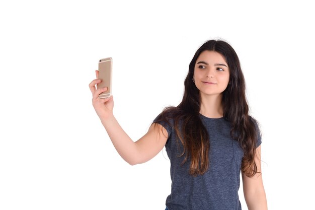 Ritratto di giovane bella donna che cattura un selfie con il suo telefono cellulare isolato in uno studio