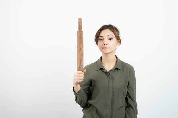 Ritratto di giovane bella donna che tiene mattarello in legno. Foto di alta qualità