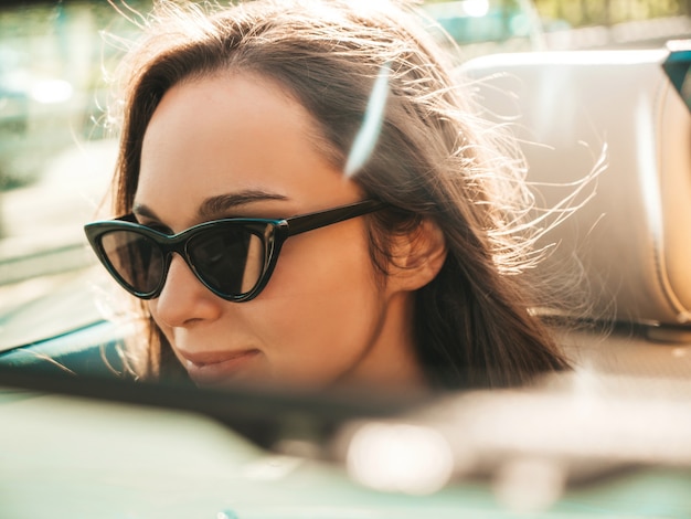 Ritratto di giovane bella e sorridente ragazza hipster in auto decappottabile