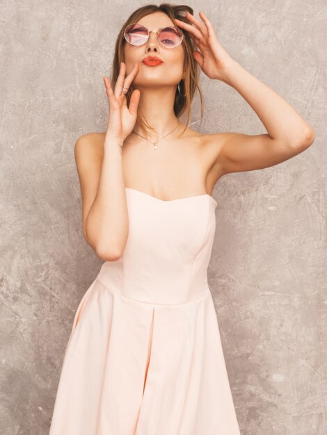 Ritratto di giovane bella ragazza sorridente in abito rosa chiaro estivo alla moda. Posa sexy donna spensierata. Divertimento del modello positivo
