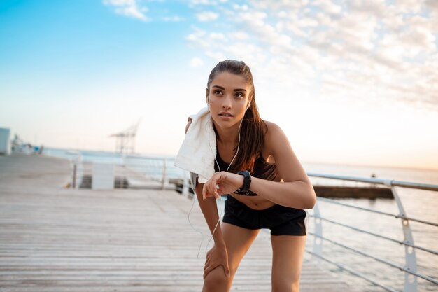 Ritratto di giovane bella ragazza sportiva ad alba sopra la spiaggia.