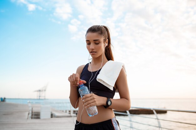 Ritratto di giovane bella ragazza sportiva ad alba sopra la spiaggia.