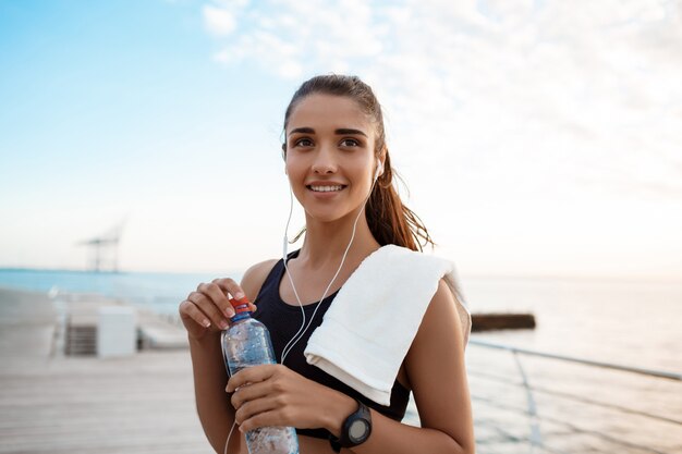 Ritratto di giovane bella ragazza sportiva ad alba sopra la spiaggia.