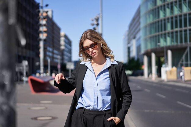 Ritratto di giovane commessa donna aziendale sicura in giacca e occhiali da sole che sembra sicuro di sé