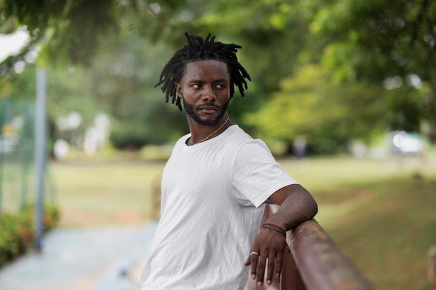 Ritratto di giovane con dreadlocks afro e t-shirt bianca all'aperto