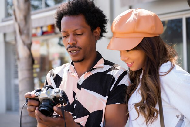 Ritratto di giovane coppia turistica che utilizza la macchina fotografica e scatta fotografie in città