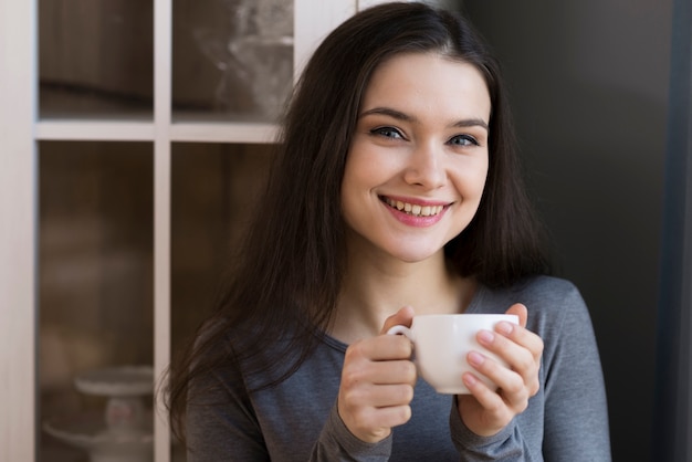 Ritratto di giovane donna adorabile che tiene una tazza di caffè