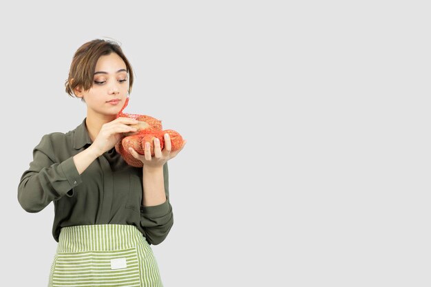 Ritratto di giovane donna adorabile dell'agricoltore che tiene le patate in borsa. Foto di alta qualità