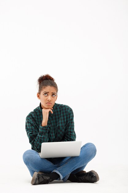 Ritratto di giovane donna africana con il computer portatile su bianco