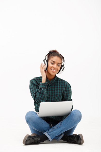 Ritratto di giovane donna africana con il computer portatile su bianco
