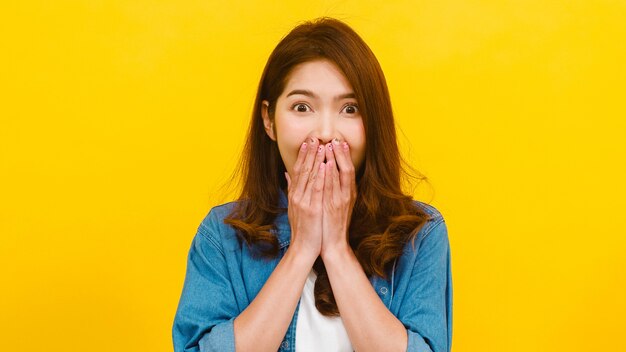 Ritratto di giovane donna asiatica con espressione positiva, gioiosa sorpresa funky, vestita in abiti casual e guardando la telecamera sul muro giallo. La donna felice adorabile felice si rallegra del successo.