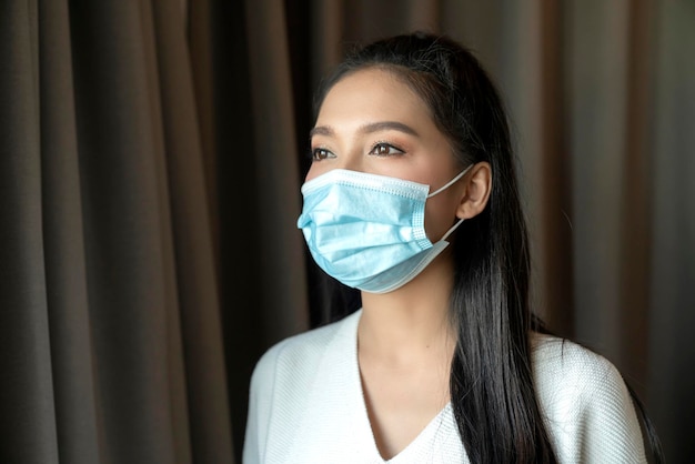 Ritratto di giovane donna asiatica indossa maschera medica per il viso pandemia coronavirus malattia quarantena in casa concetto di prevenzione delle epidemie Covid19