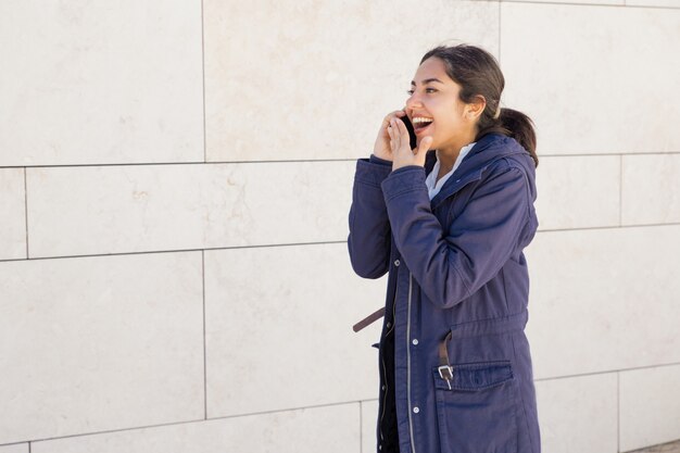 Ritratto di giovane donna asiatica spettegolare sul telefono cellulare all&#39;aperto