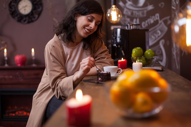 Ritratto di giovane donna caucasica attraente che mangia la torta al bancone del bar in una caffetteria hipster. Bella donna che mangia una torta saporita in una caffetteria.