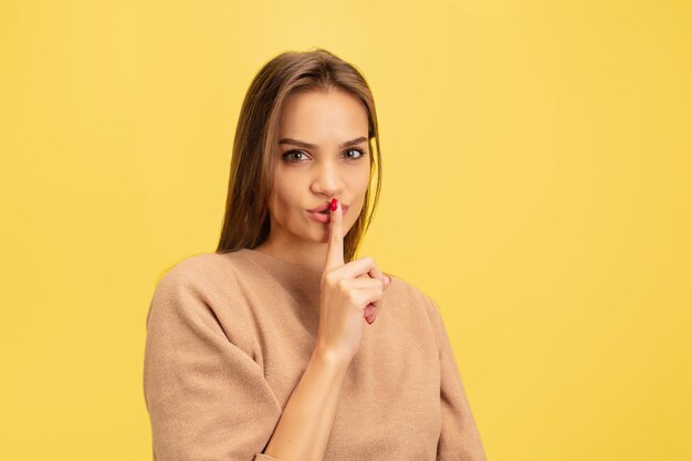 Ritratto di giovane donna caucasica con emozioni luminose isolate su studio giallo