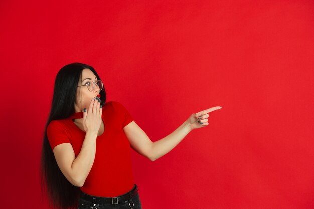 Ritratto di giovane donna caucasica con emozioni luminose su sfondo rosso studio