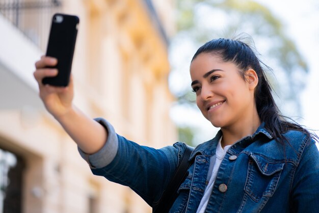 Ritratto di giovane donna che cattura selfie con il suo telefono mophile mentre si trovava all'aperto