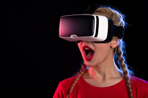 Ritratto di giovane donna che gioca con la realtà virtuale sul gioco ad ultrasuoni visivo scuro d