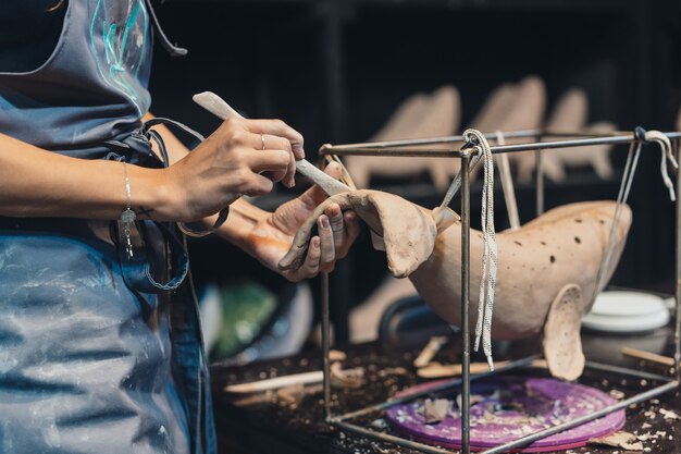 Ritratto di giovane donna che gode del lavoro preferito in officina. Il vasaio lavora con cura sulla balena d'argilla