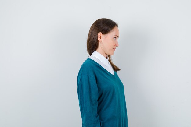 Ritratto di giovane donna che guarda dritto in avanti con un maglione su una camicia bianca e che sembra concentrata