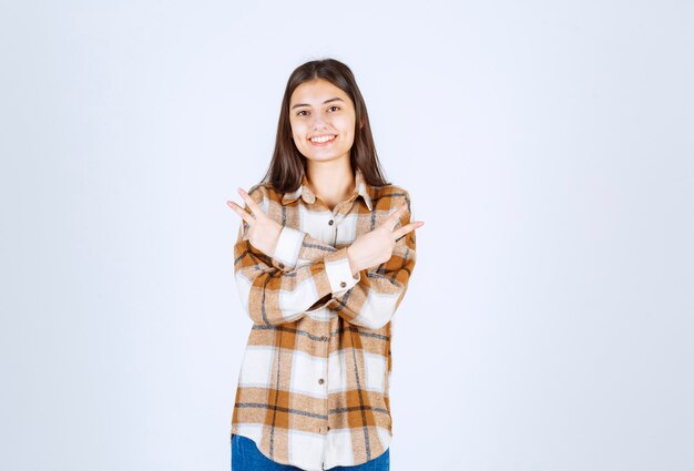 Ritratto di giovane donna che guarda felicemente la fotocamera sul muro bianco.