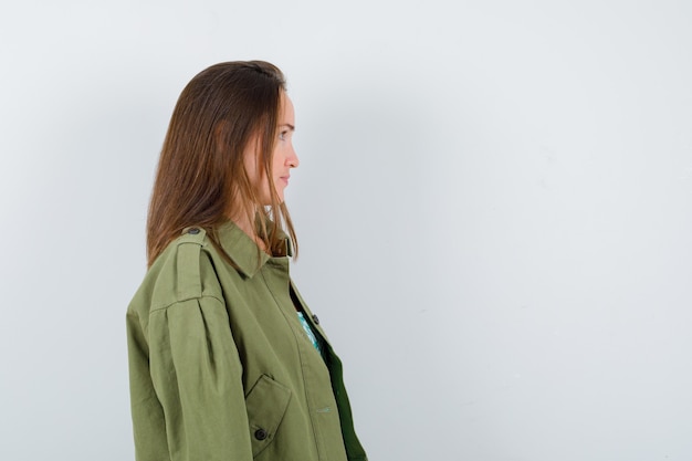 Ritratto di giovane donna che guarda lontano, in piedi di lato in giacca verde e sembra concentrata