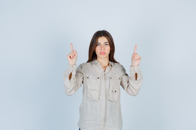 Ritratto di giovane donna che indica in casual, jeans e guardando fiducioso vista frontale
