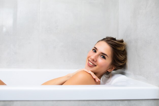 Ritratto di giovane donna che si rilassa nella vasca da bagno a casa