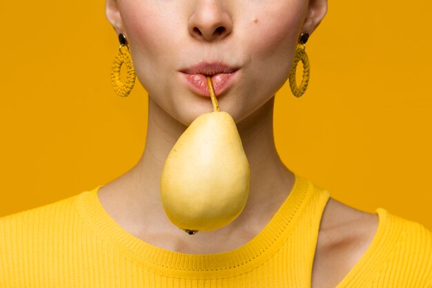 Ritratto di giovane donna che tiene pera in bocca