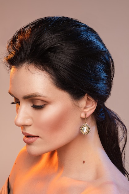 Ritratto di giovane donna con bel trucco e orecchini con gemme isolate