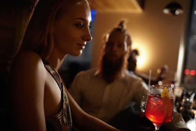 Ritratto di giovane donna con capelli biondi che tengono cocktail