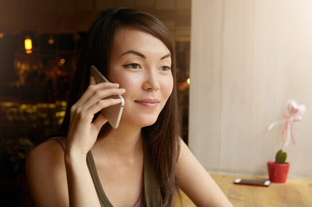 Ritratto di giovane donna con capelli castani utilizzando il telefono