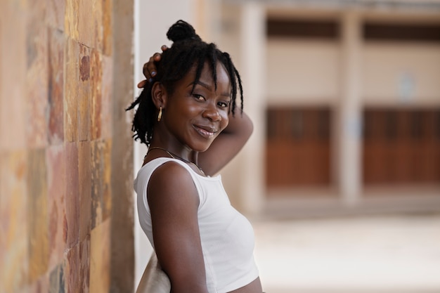 Ritratto di giovane donna con dreadlocks afro in posa all'esterno