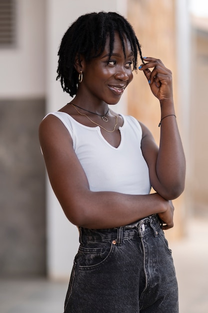 Ritratto di giovane donna con dreadlocks afro in posa all'esterno