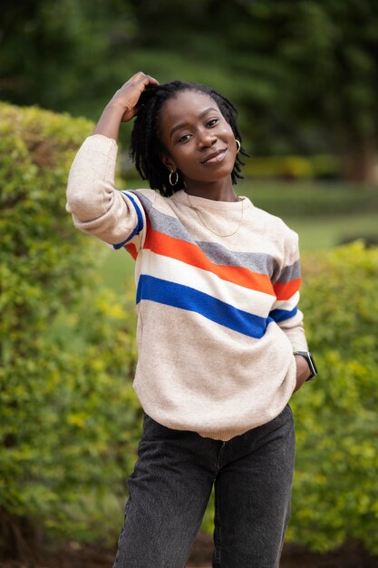 Ritratto di giovane donna con dreadlocks afro in posa all'esterno