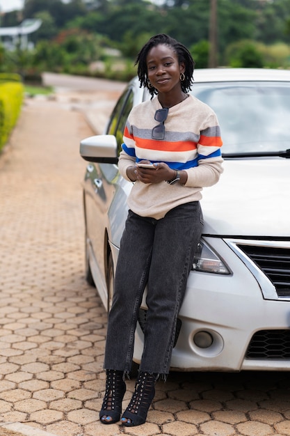 Ritratto di giovane donna con dreadlocks afro in posa con auto