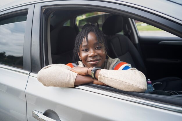 Ritratto di giovane donna con dreadlocks afro in posa con auto