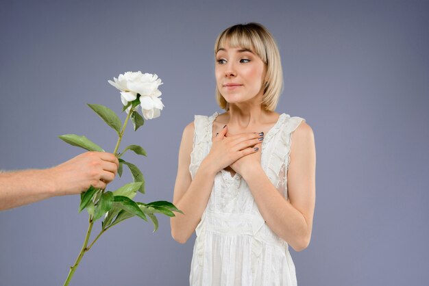 Ritratto di giovane donna con fiore sul muro grigio