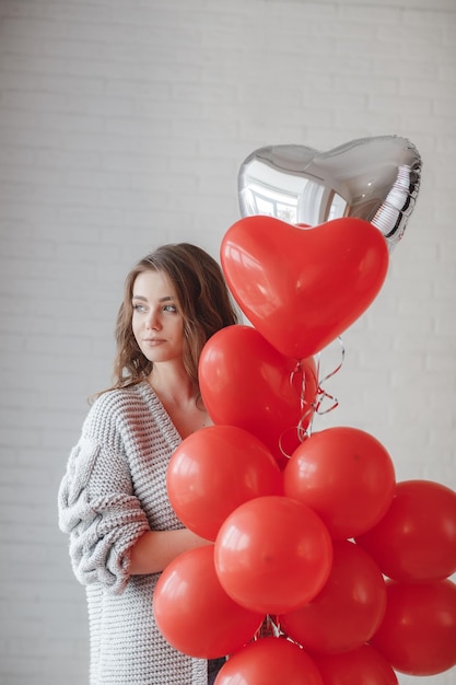 ritratto di giovane donna con palloncini rossi al coperto