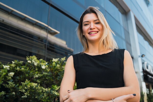 Ritratto di giovane donna d'affari in piedi al di fuori degli edifici per uffici. Concetto di affari e successo.